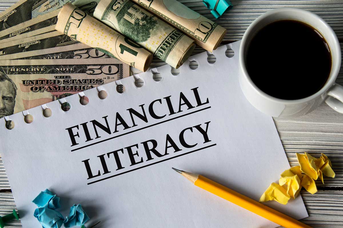 Paper reading "Financial Literacy" next to coffee, pencil, and cash