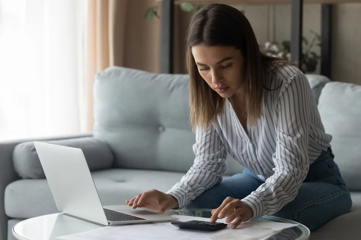 Woman working at laptop with calculator