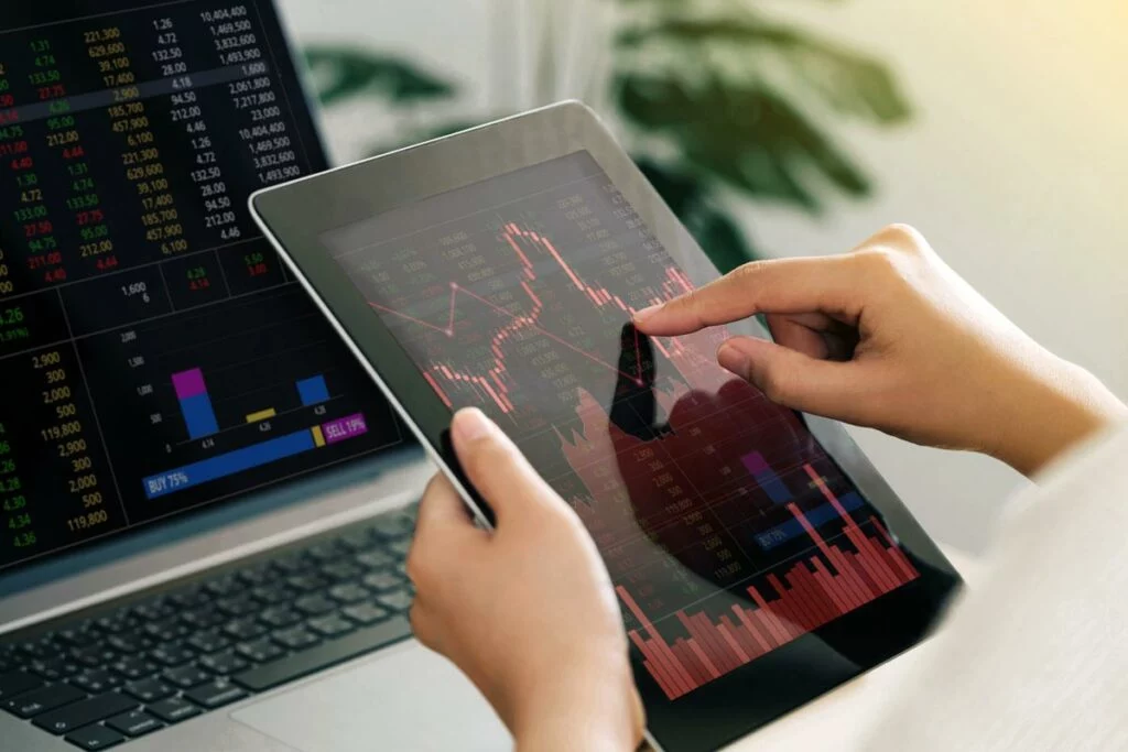 Woman holding tablet showing red, negative-trending stock data