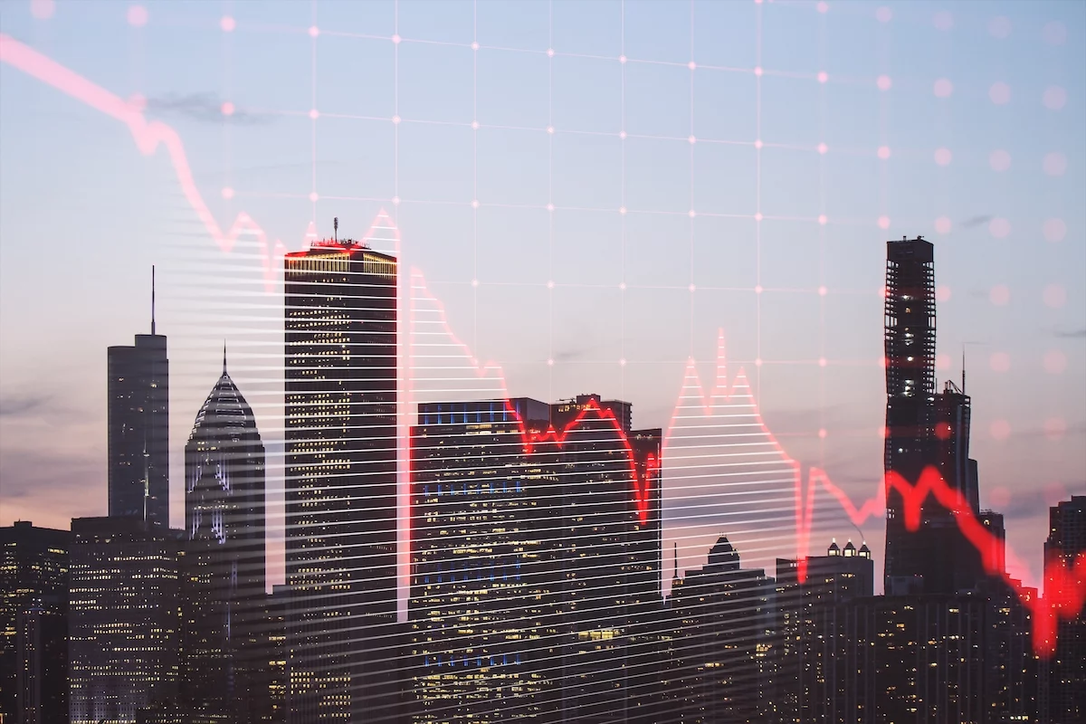 Downward-trending red line chart over image of city skyline