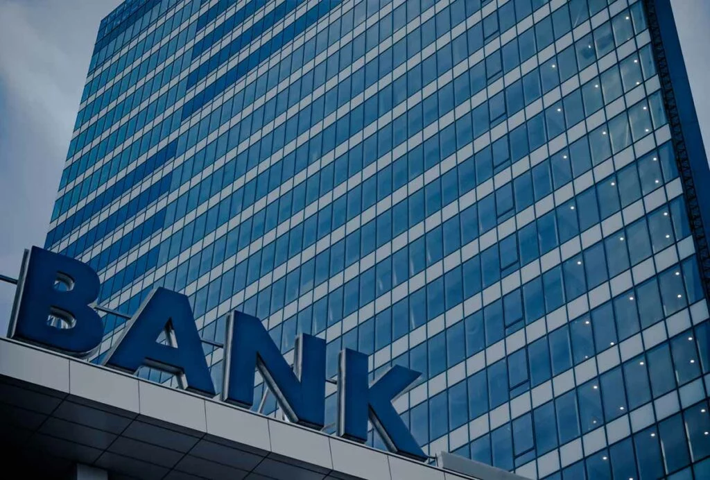 Bank sign in front of tall glass building