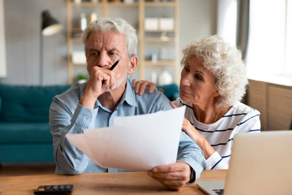 Concerned older couple with paper and laptop