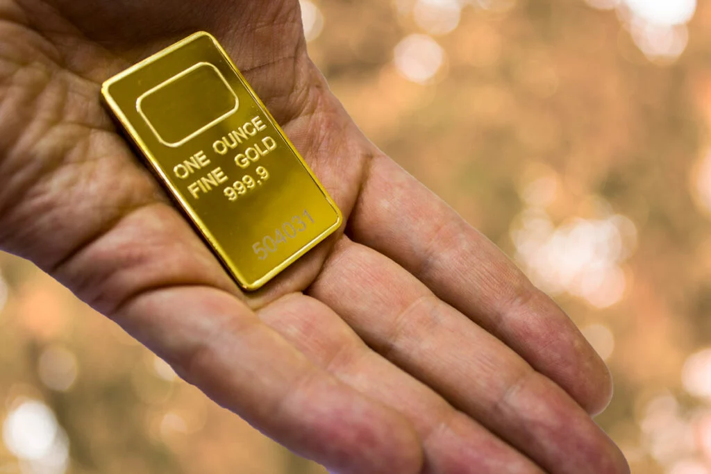 Hand holding 1 oz. gold bar