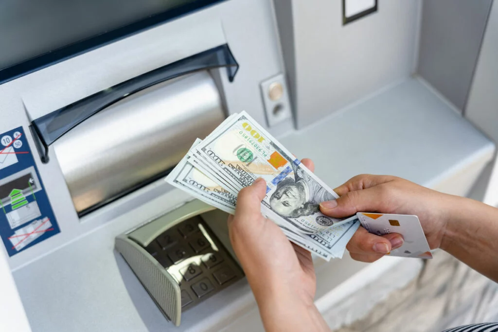 Hands taking cash withdrawal from ATM