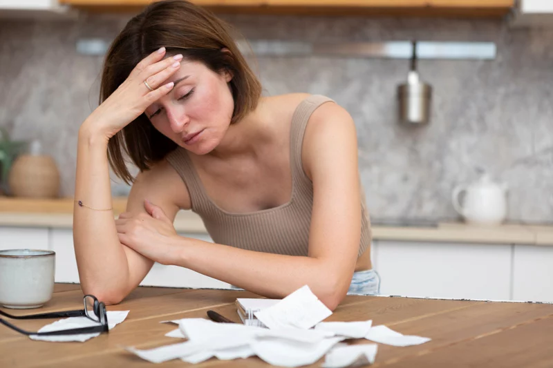 Unhappy woman looking at pile of receipts