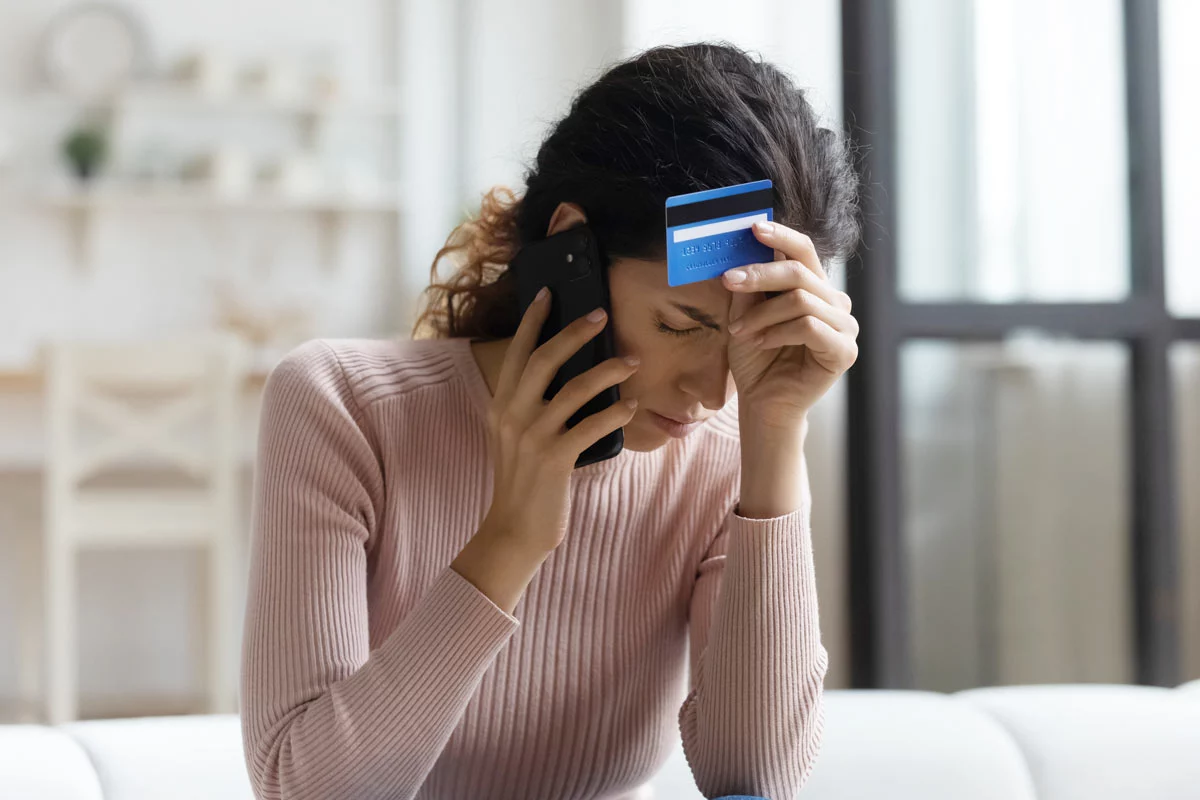 Unhappy woman on phone holding credit card