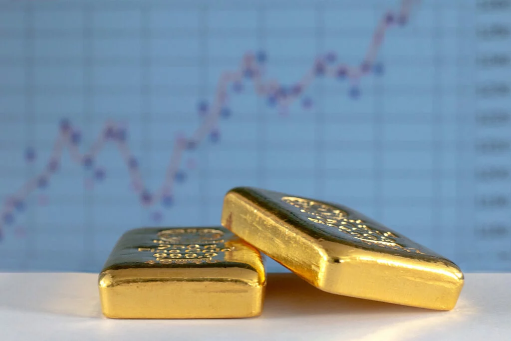 Gold bars in front of upward-trending data chart