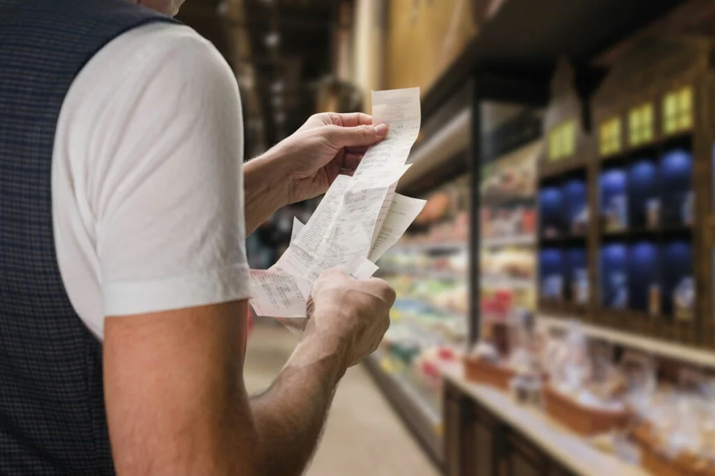 Person holding receipts in grocery store aisle