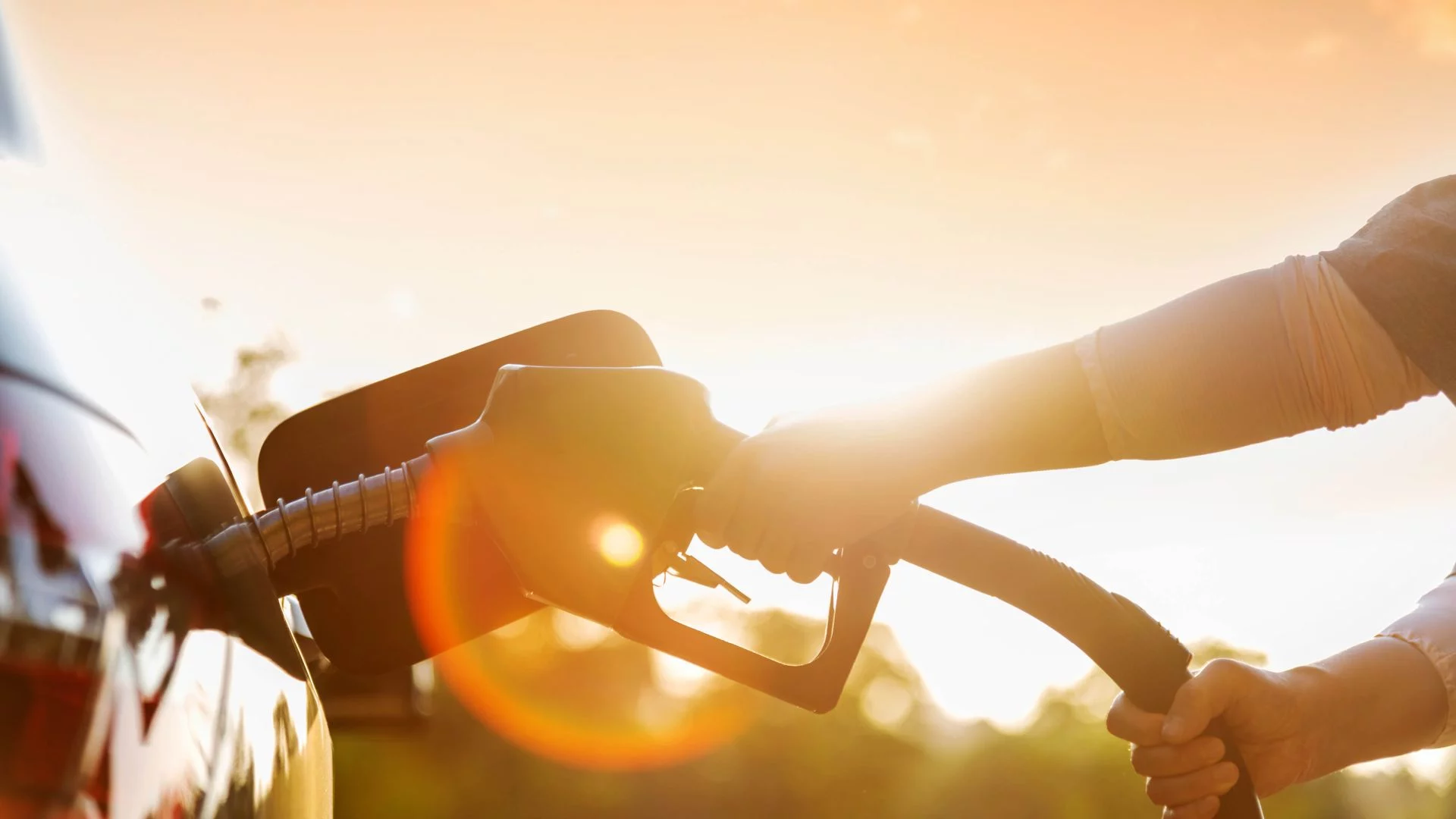Silhouette of gas pump nozzle in front of sun